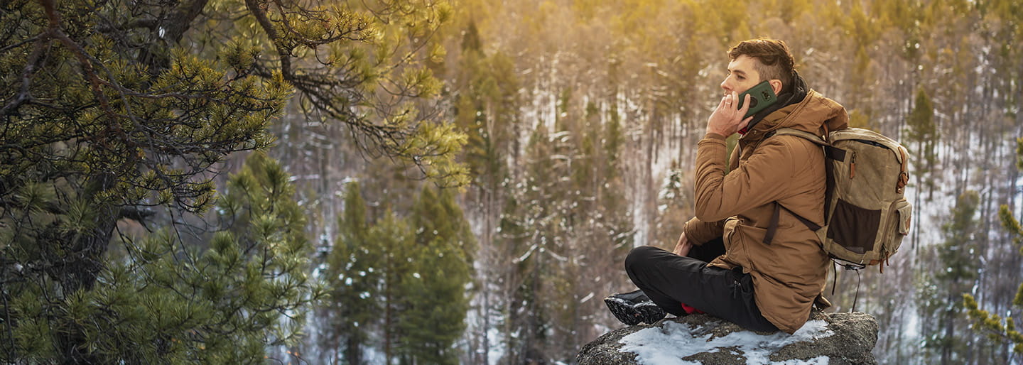 Man traveling in national forest and making a phone call using mobile connectivity