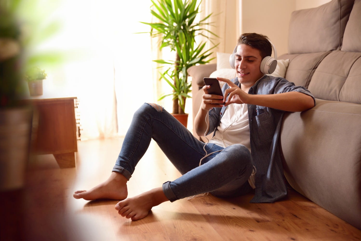 Teen sitting on floor using a smartphone in living room