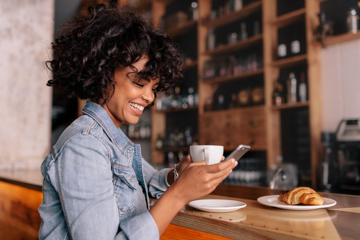 Smiling woman using smart phone in a modern cafe